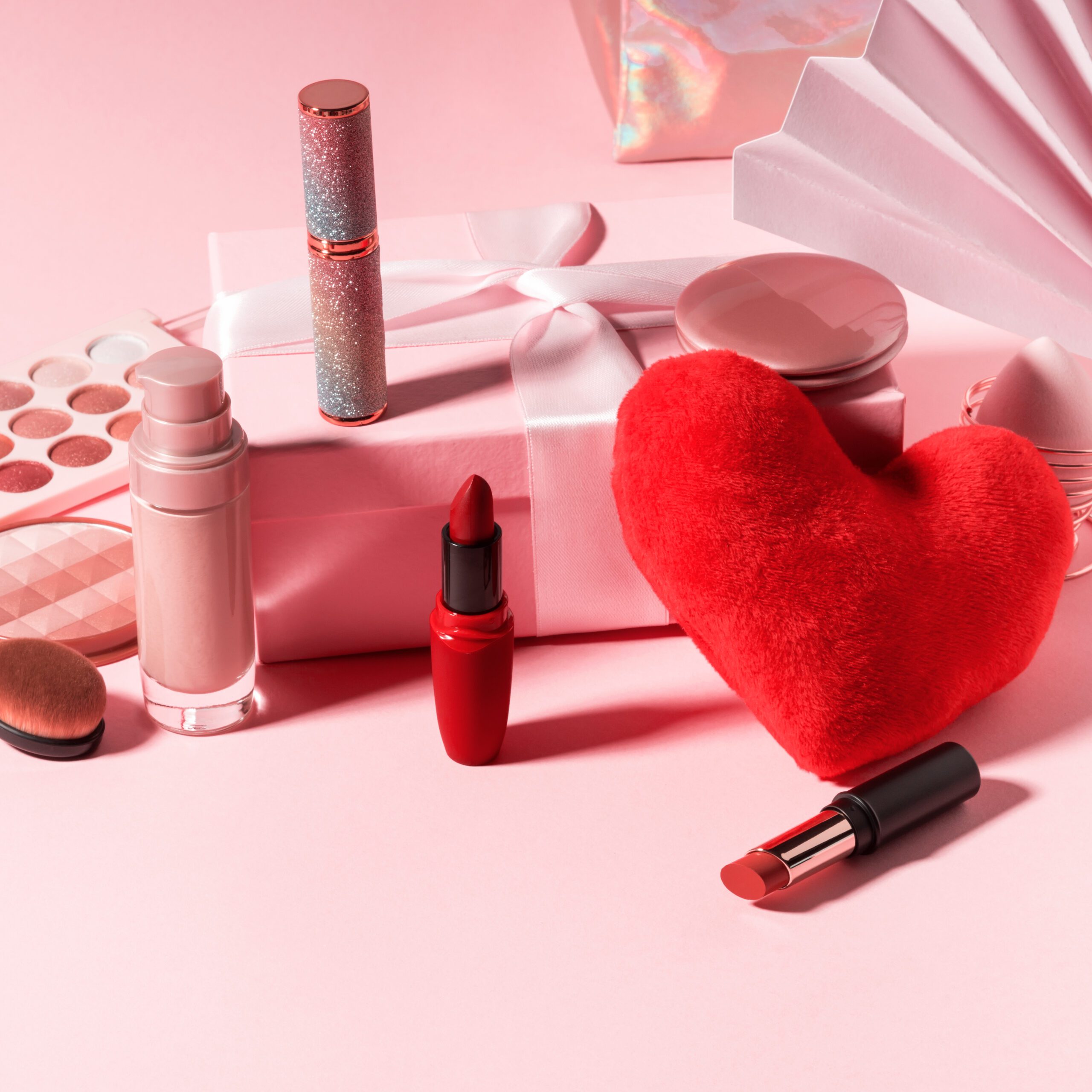 Cosmetics beauty background with red heart on pink