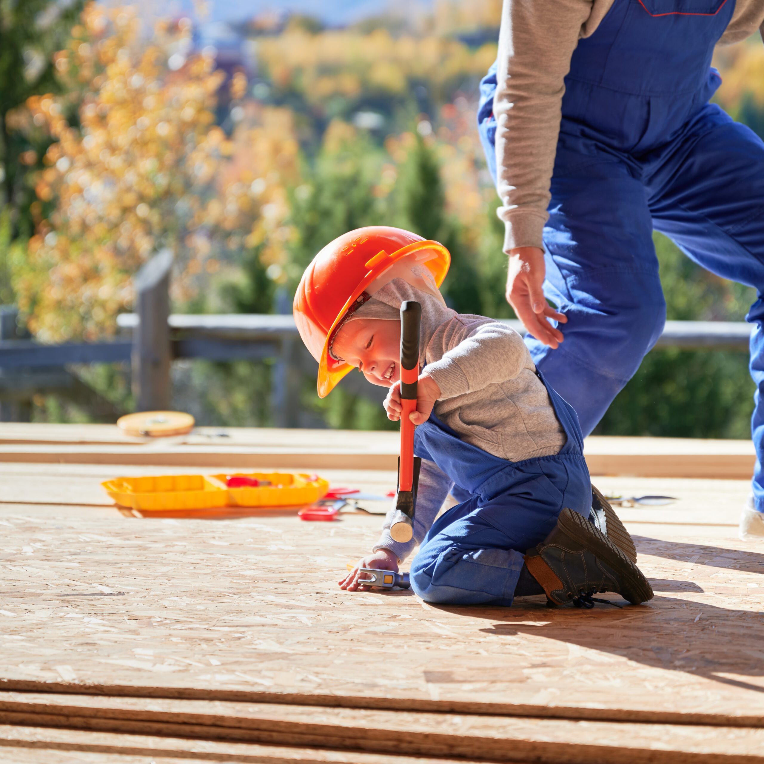 Father with toddler son building wooden frame house.